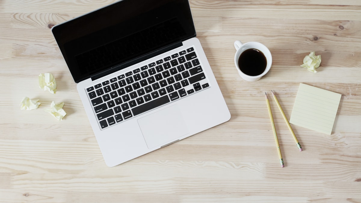 A laptop and a cup of coffee on a light wooden desk